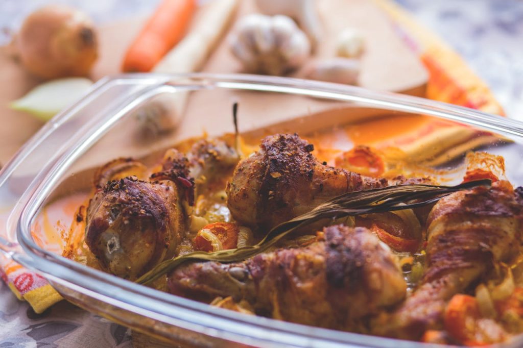 Home Delicious roasted chicken drumsticks with vegetables in a glass dish, perfect for a family meal.