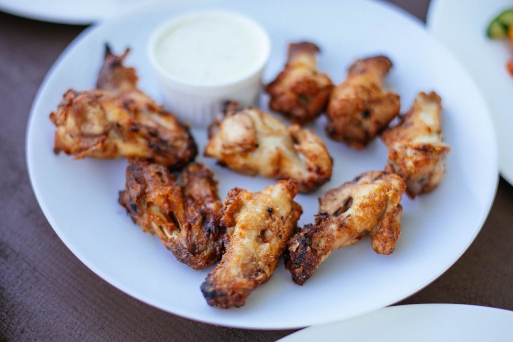 Home Delicious crispy chicken wings served on a white plate with dipping sauce.